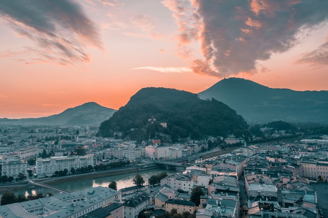 View of Kapuzinerberg and Gaisberg above the Salzach at sunrise in Salzburg old town.