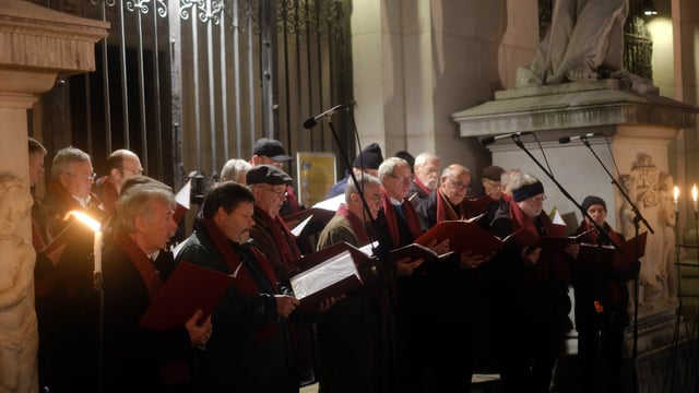 Advent choir performing at the entrance gate of Salzburg Cathedral with stone columns and statuary