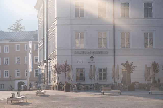 Morning sun flare across the Salzburg Museum corner of the Neue Residenz on Mozartplatz.