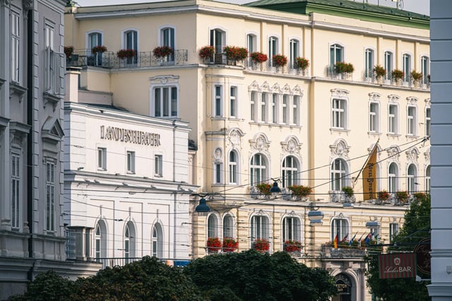 Salzburger Landestheater facade beside Hotel Sacher with flower balconies in Salzburg.