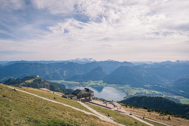 From the grassy Schafberg summit plateau the eye runs past the small railway station down to the Wolfgangsee and on to range after range ending in the snowy Dachstein.