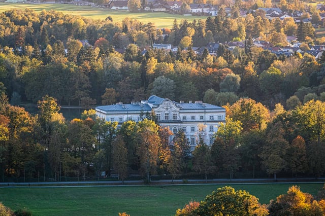 Schloss Leopoldskron palace nestled among autumn foliage seen from the Monchsberg in Salzburg.