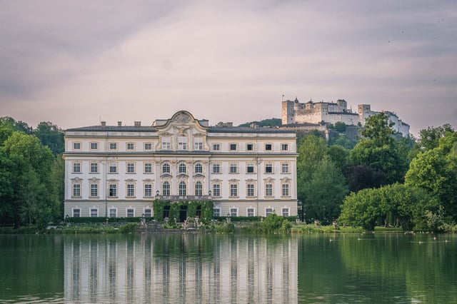 Schloss Leopoldskron reflected in Leopoldskroner Weiher with Hohensalzburg Fortress behind in Salzburg