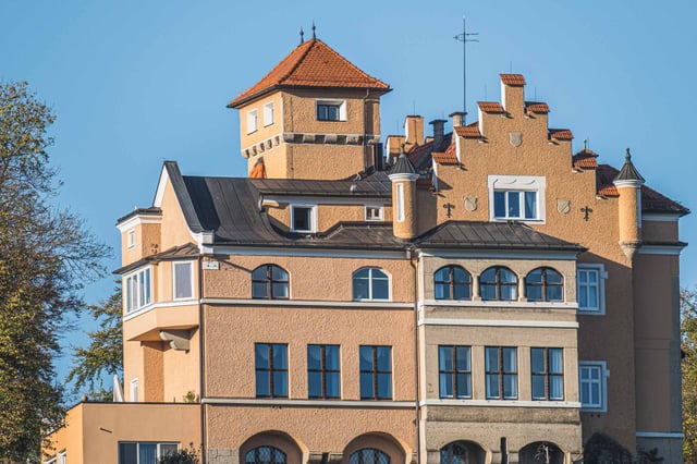 Schloss Moenchstein hotel facade with turret and embedded coat of arms under blue sky on Moenchsberg in Salzburg