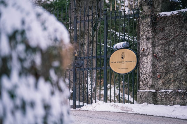 Entrance gate of Hotel Schloss Moenchstein with wrought iron and brand medallion in the snow.