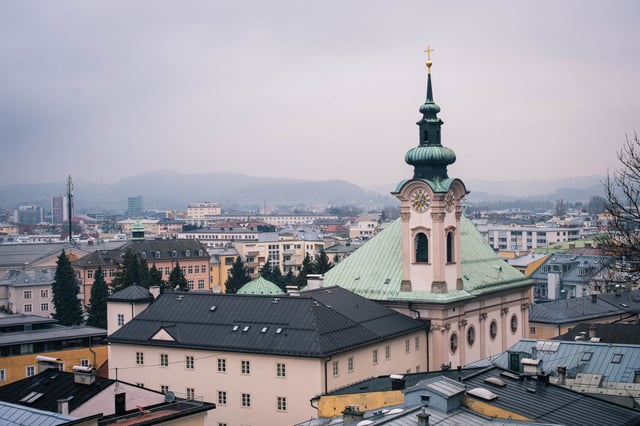 Green onion-domed tower of Sebastianskirche rises over Neustadt rooftops in Salzburg
