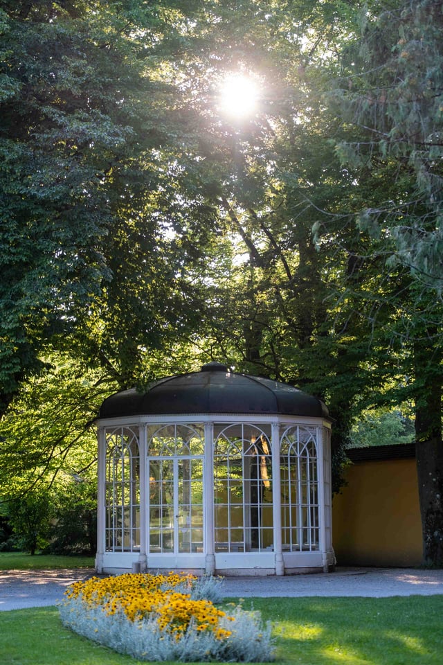 Sound of Music pavilion framed by yellow flowerbed and trees at Hellbrunn in Salzburg.