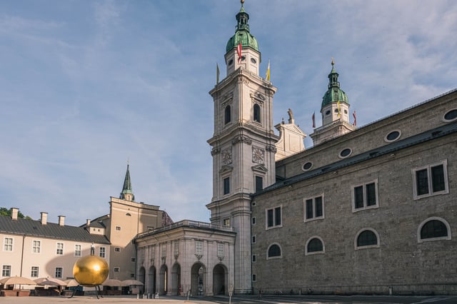 Sphaera golden ball sculpture in front of Salzburg Cathedral towers on Kapitelplatz in Salzburg