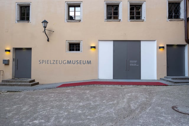 Spielzeugmuseum entrance doors with red carpet and lettering in historic courtyard in Salzburg