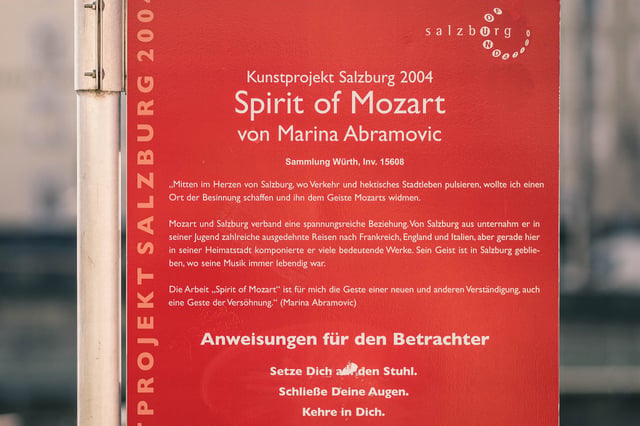 Red information plaque describes the Spirit of Mozart art installation by Marina Abramovic in Salzburg.