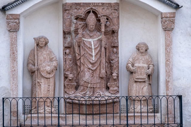 Renaissance stone relief of a bishop saint flanked by two figures with Anno Domini 1515 inscription at St Georges Chapel inside Hohensalzburg Fortress (Leonhard von Keutschach)