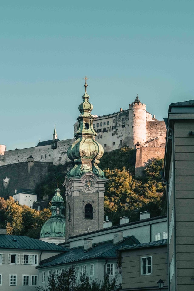 Green onion-dome tower of Stift St Peter below Hohensalzburg fortress in Salzburg old town