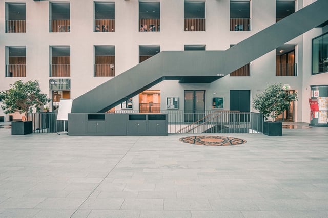 Modern courtyard with diagonal metal stairs and surrounding glass-balcony floors at the Universitaet Mozarteum building in Salzburg