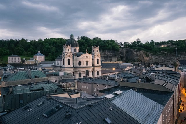 Kollegienkirche baroque facade and dome rise above Altstadt rooftops at dusk in Salzburg