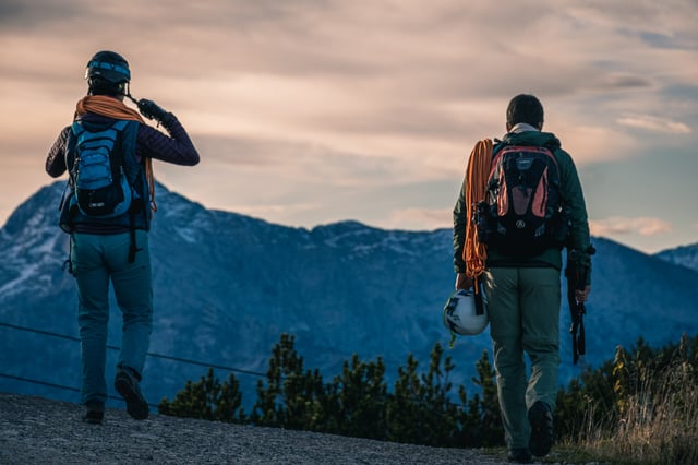 Two climbers with ropes and helmets walk along the Untersberg summit plateau at dawn.