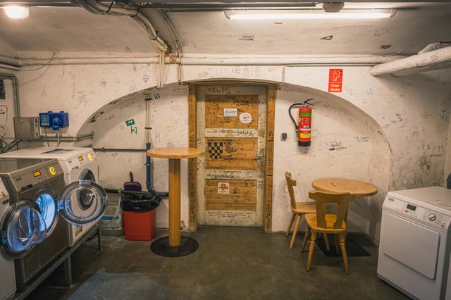 Guest laundry room with vintage washing machines and graffiti covered walls inside YoHo Hostel in Salzburg