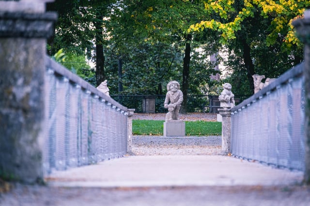 Stone dwarf statues along pathway in the Zwerglgarten dwarf garden in Mirabell Gardens Salzburg.
